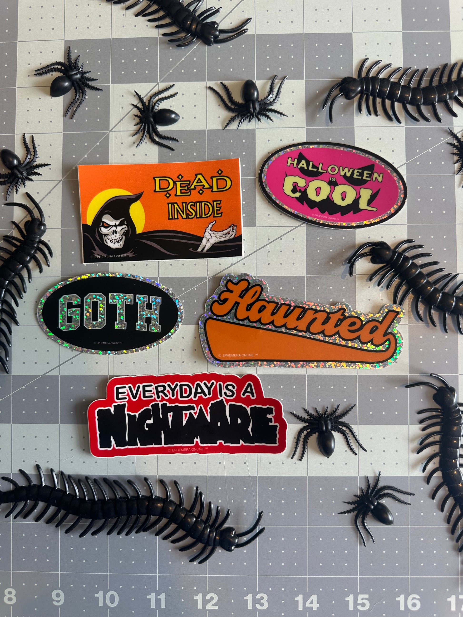 Halloween-themed stickers on a grid background with spiders.